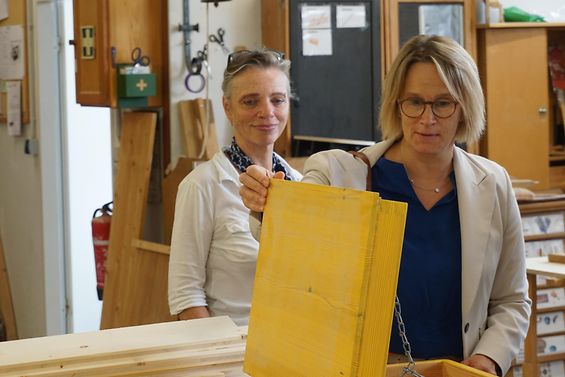 Sozialsenatorin Melanie Schlotzhauer betrachtet eine Holzkiste, die in der Holzwerkstatt von Nutzmüll e. V. gebaut wurde.